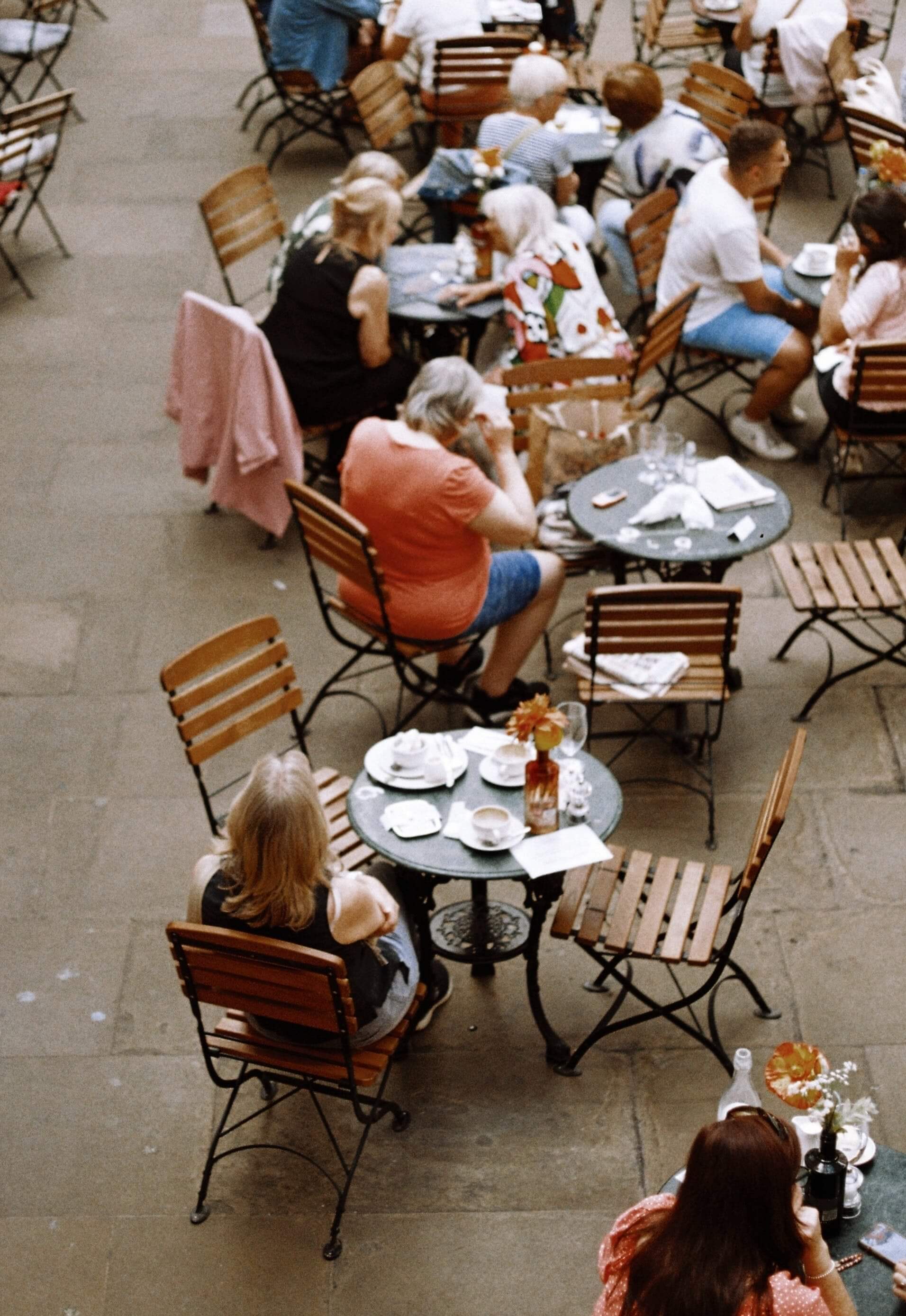 photo of people sitting at tables outside
